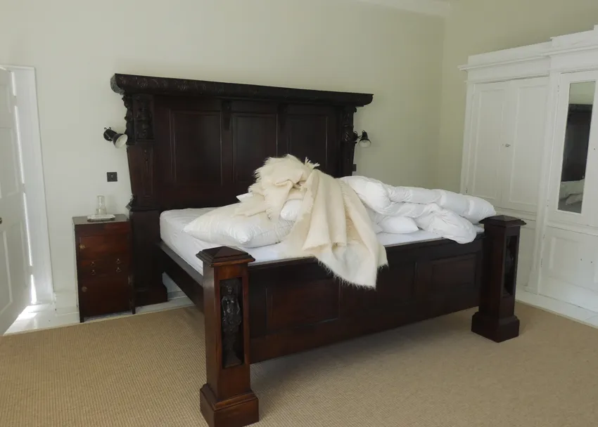 traditional bedroom in wales with heavy timber bed and simple interior finish