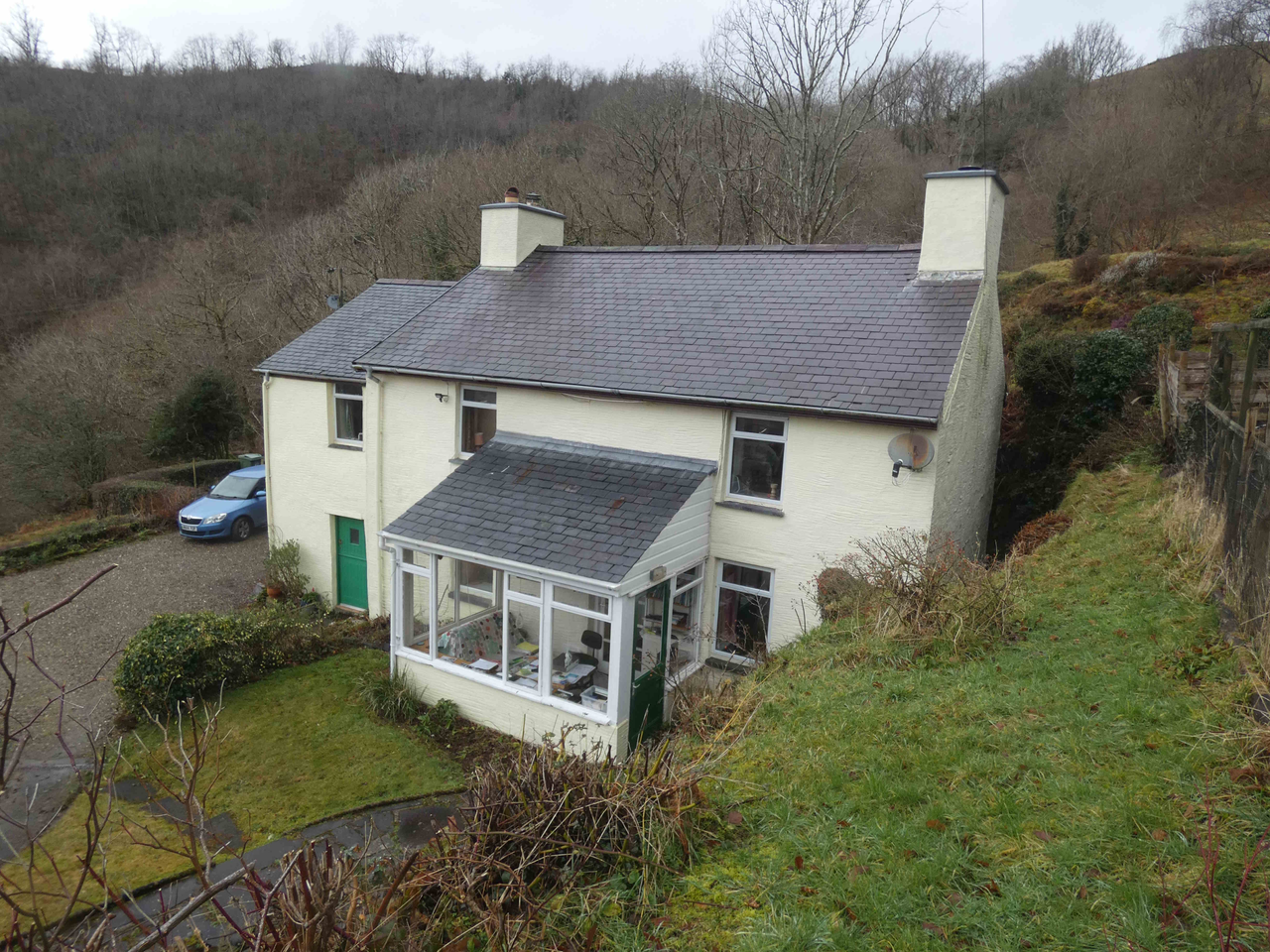 Traditional rendered house in Wales with conservatory extension on a sloping garden site